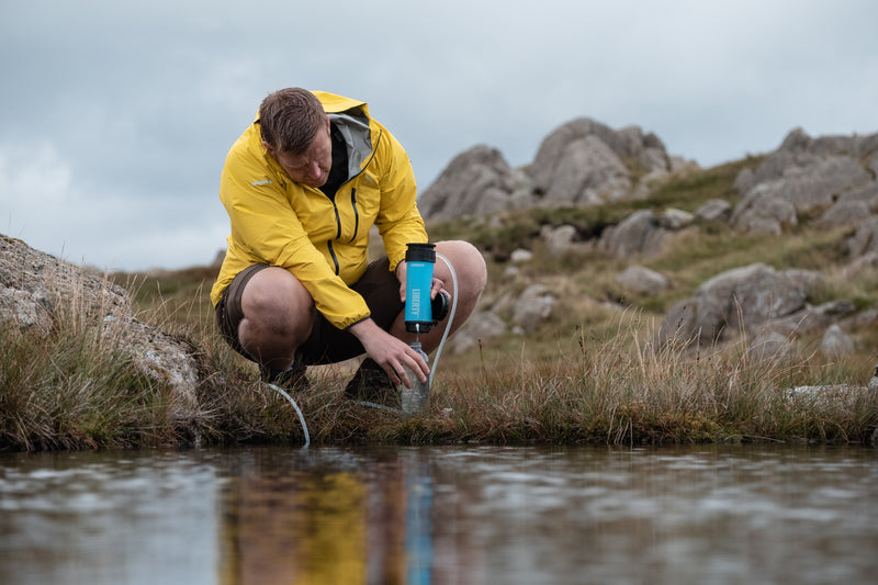 Load image into Gallery viewer, A man purifying lake water using a LifeSaver Liberty bottle

