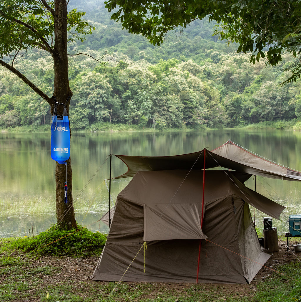 Camping tent by a lake and a Lifeline Gravity Bag hanging from a tree