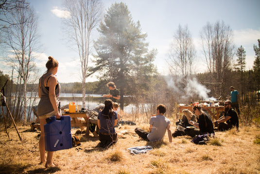 A group of campers cooking by a lake with a LifeSaver Jerrycan
